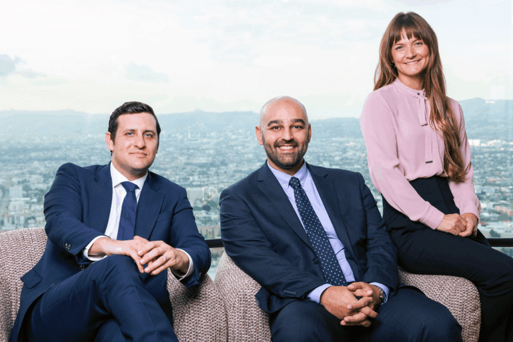 Three partners at Seyfnia & Prybylo, LLP—Garrett Prybylo, Farzad Seyfnia, and their colleague—seated together in an office with the Los Angeles skyline behind them